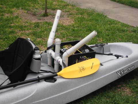 1953 Ford Mainline - Kayak outfitted with a DIY PVC rod holder system and a yellow paddle rests on grass.