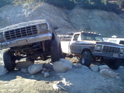 1978 Ford Bronco - A truck is seen towing a trailer on a rough, unpaved surface.