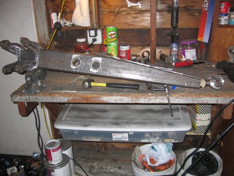 1989 Ford Bronco - Custom suspension part fabricated from steel, clamped in a vise on a workbench.