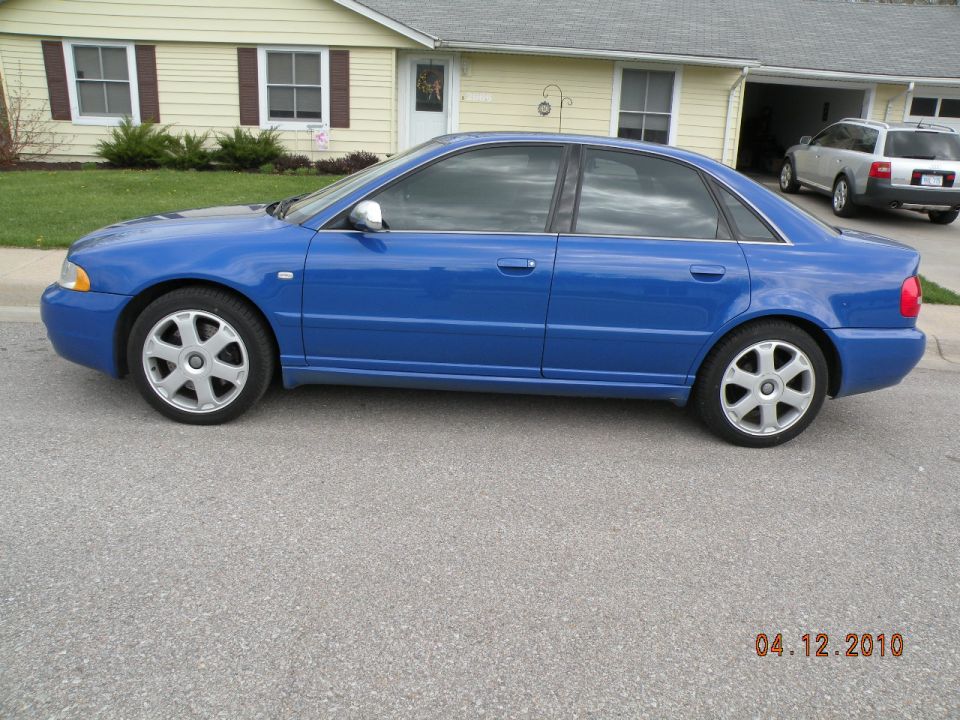 Bright blue B5 Audi S4 sedan side profile with Avus-style wheels on a residential street