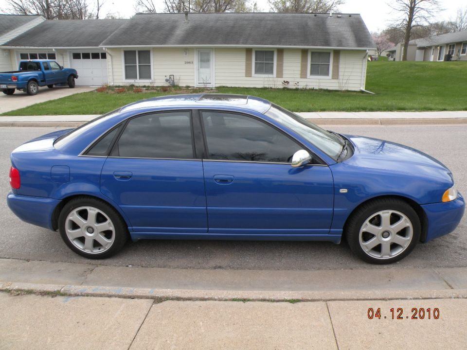 Blue Audi S4 sedan side profile parked at suburban curb on seven-spoke alloy wheels
