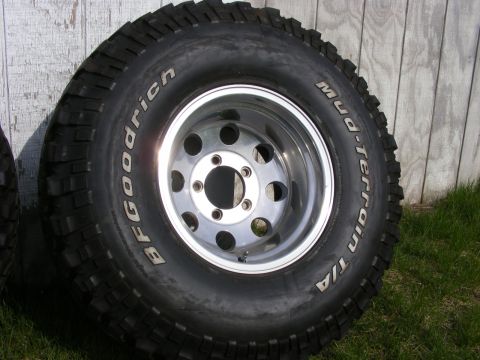 1990 Ford Bronco - A close-up of a BFGoodrich Mud-Terrain T/A tire and a chrome rim is shown against a wooden background.