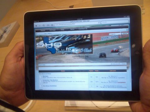 1993 Ford Taurus - Tablet displays a car club website with forum content and a background image of race cars.