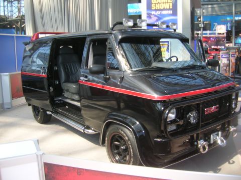 1996 Ford Bronco - This black GMC van features a distinctive red stripe, roof-mounted lights, and a heavy-duty front brush guard.