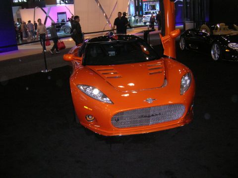 1996 Ford Bronco - An orange Spyker sports car is displayed at an auto show with its doors open.