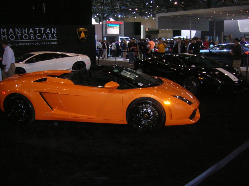 Orange convertible sports car with black wheels and black interior, viewed from the front three-quarter angle