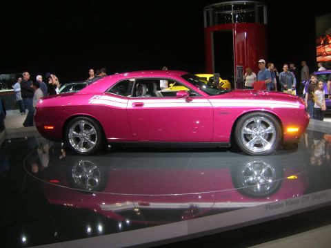 1996 Ford Bronco - A pink Dodge Challenger with white racing stripes is shown on a display platform.