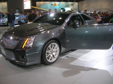 1996 Ford Bronco - A dark gray Cadillac CTS-V Coupe is displayed with its door open, attracting attention at an auto show.