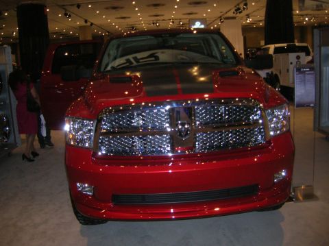 1996 Ford Bronco - A red Dodge Ram truck is displayed indoors with its driver's side door open.