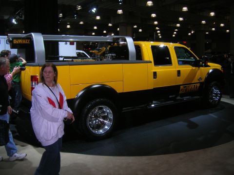 1996 Ford Bronco - A yellow DeWalt service truck is displayed indoors with people around it.