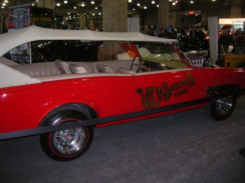 1996 Ford Bronco - A red convertible with a distinctive "Monkees Mobile" decal is displayed indoors.