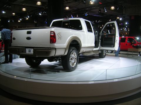 1996 Ford Bronco - White Ford Super Duty pickup truck displayed with its driver's door open, another red truck is in the background.