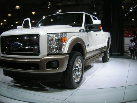 1996 Ford Bronco - A white and brown Ford F-Series truck is displayed indoors with its doors open.