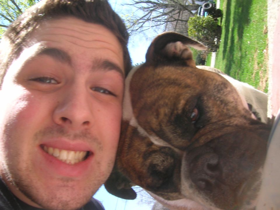 Man and brindle dog pose for a selfie outdoors