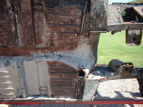 1964 Ford Fairlane - The undercarriage of a severely rusted vehicle frame and floor pan is visible, indicating significant deterioration.
