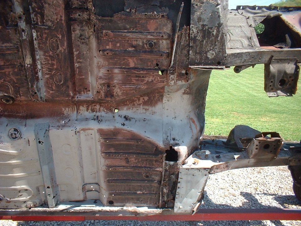 rusted car frame and floor pan showing extensive corrosion and structural damage