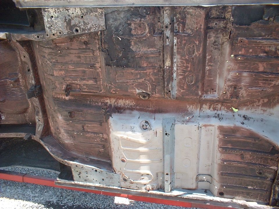 Underside of a car showing rusted floor pans and frame rails