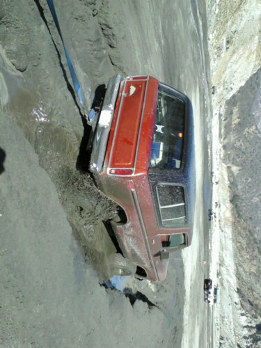 1978 Ford Bronco - A red and black 1978 Ford Bronco is stuck in a muddy ravine, with a strap attached to pull it out.
