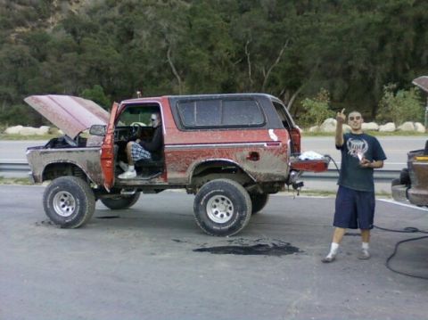 1978 Ford Bronco - A man stands next to a red 1978 Ford Bronco with its hood up, parked on asphalt.