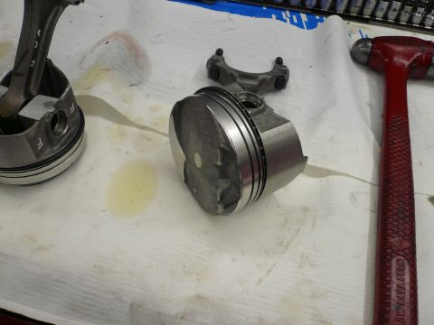 1975 Ford Ranchero - Engine parts, including pistons and a connecting rod, are laid out on a white cloth next to a red hammer.
