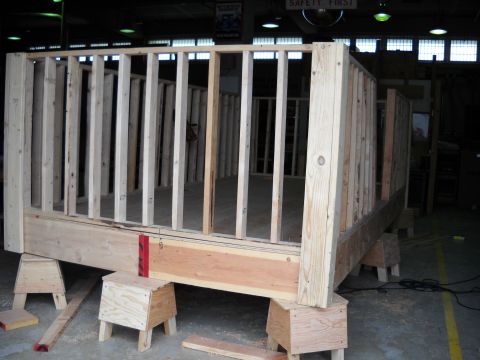 1986 Ford Bronco - A wooden framing structure, possibly for a stage or platform, is elevated on sawhorses within a workshop environment.