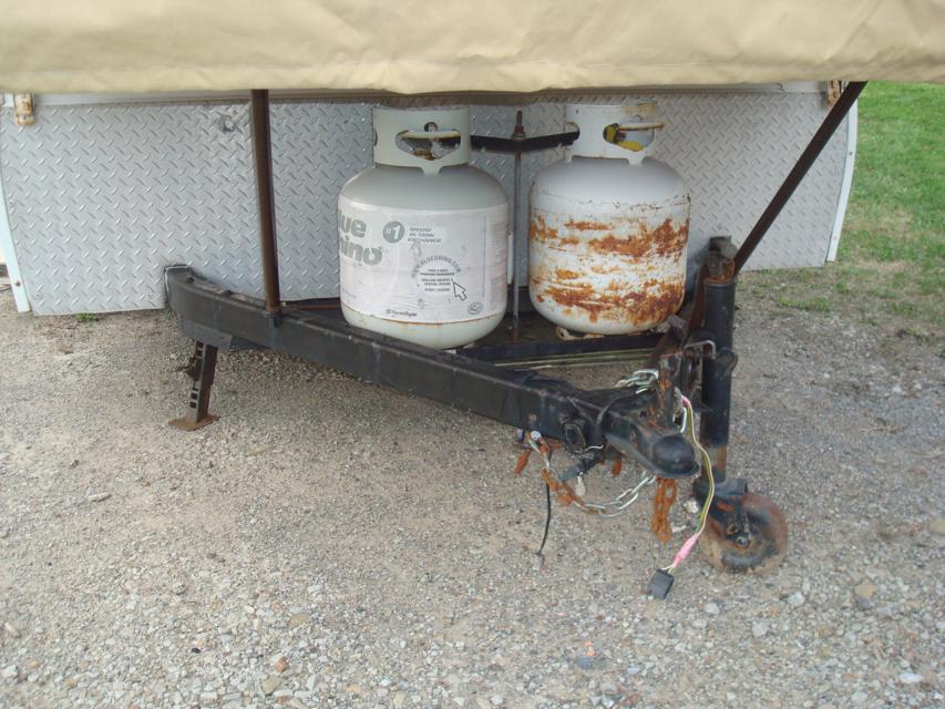 Two propane tanks on a trailer hitch, one rusted