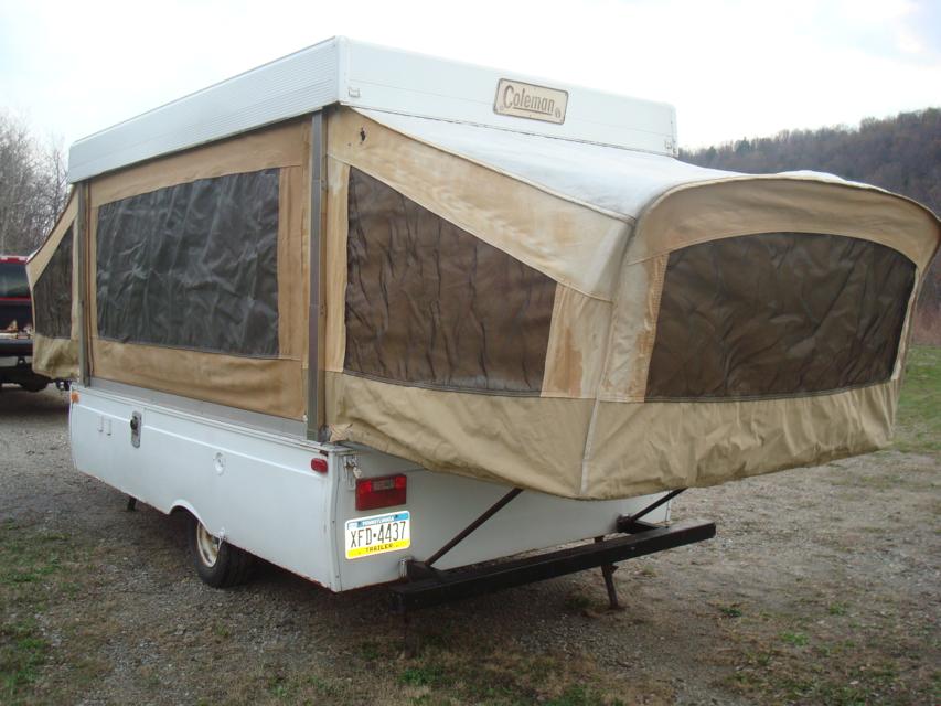 White pop-up camper trailer with tan canvas, viewed from the rear