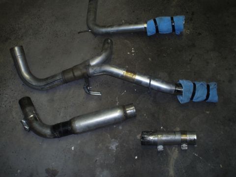 2002 Chevrolet Camaro - Several sections of a vehicle's exhaust system are shown, including pipes and mufflers, on a workshop floor.