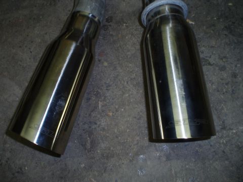 2002 Chevrolet Camaro - Close-up of two chrome exhaust tips, each bearing an etched 'SS' logo, against a concrete background.