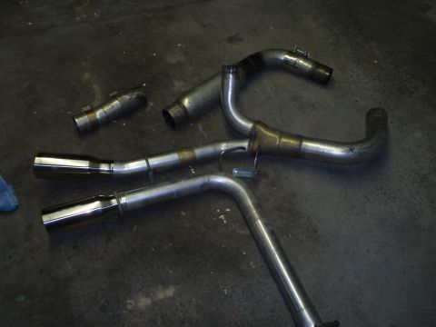 2002 Chevrolet Camaro - Aftermarket exhaust components are laid out on the floor, ready for installation.