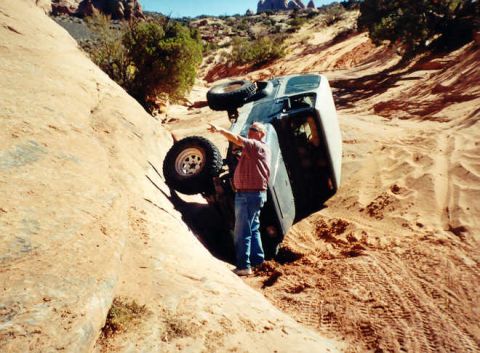 2002 Ford F-350 - A Ford F-350 has rolled onto its side while off-roading in a desert landscape.