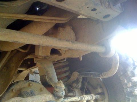 1995 Ford Bronco - Close-up of vehicle undercarriage, focusing on suspension and exhaust system parts.