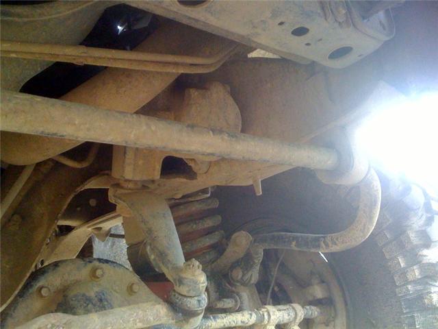 Undercarriage view showing suspension components and exhaust pipe. Watermark reads SUPERMOTORS.NET