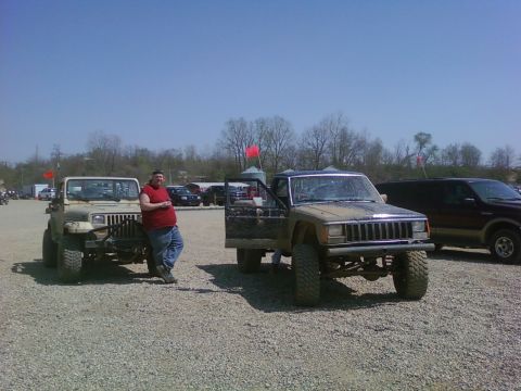 1989 Ford Bronco - Two Jeep vehicles and a man stand in a gravel lot under a clear blue sky.