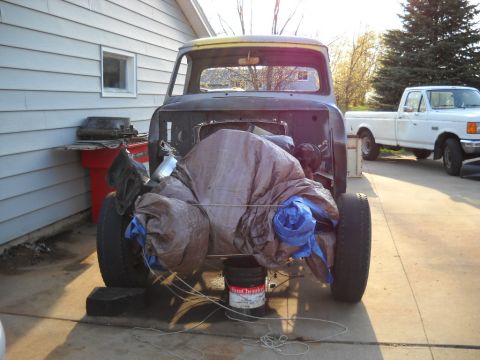 1954 Ford F-100 - A partially covered truck cab sits in a driveway next to another pickup truck.