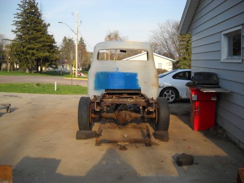 1954 Ford F-100 - This primer gray 1953 Ford F-100 truck cab and chassis is shown from the rear, with a blue patch on the back of the cab.