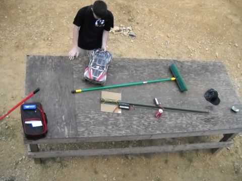 1986 Ford Bronco - A person stands over a table with a remote control car, a broom, and various tools laid out.