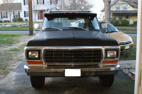 1979 Ford Bronco - Front view of a black 1979 Ford Bronco parked in a driveway with a yellow car behind it.