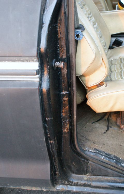 1979 Ford Bronco - Close-up of the interior door frame and seat, showing damage to the black paintwork.