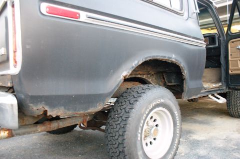 1979 Ford Bronco - The rear quarter panel of a dark gray 1978 Ford Bronco shows significant rust damage around the wheel well.