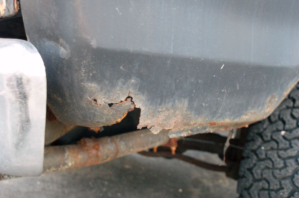 Rusted lower body panel and exhaust pipe of a vehicle