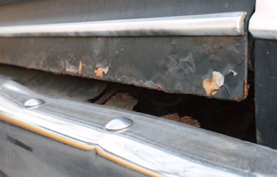 Close-up of rusted metal panel and chrome trim, with SuperMotors logo at bottom right
