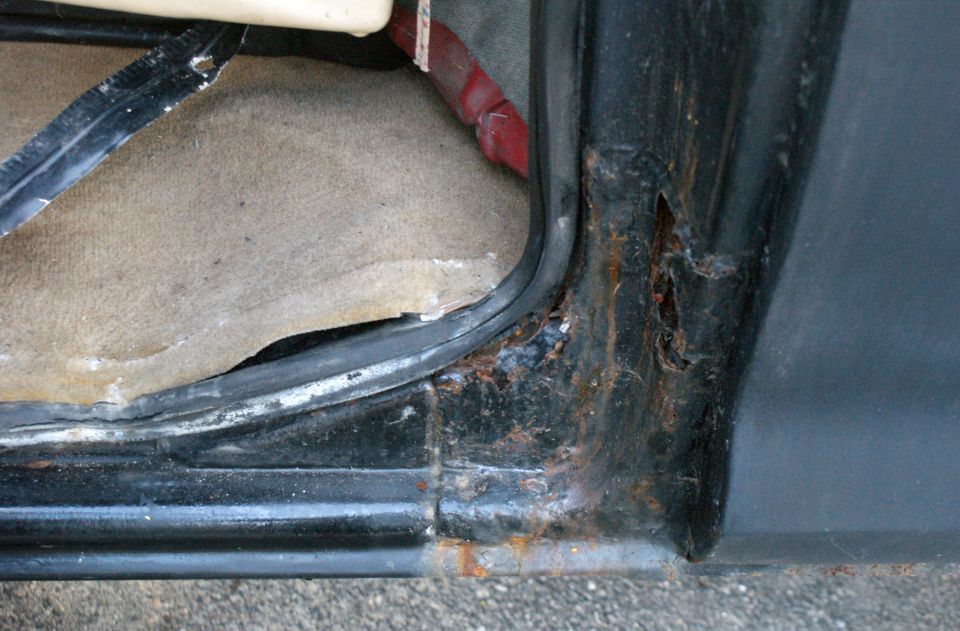 Close-up of a rusted door frame and carpet inside a vehicle