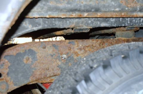 1979 Ford Bronco - Close-up view of a heavily rusted vehicle frame and tire, with visible text from Supermotors.net.