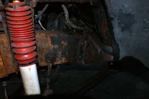 1979 Ford Bronco - The undercarriage of a vehicle shows significant rust and wear on its suspension components.