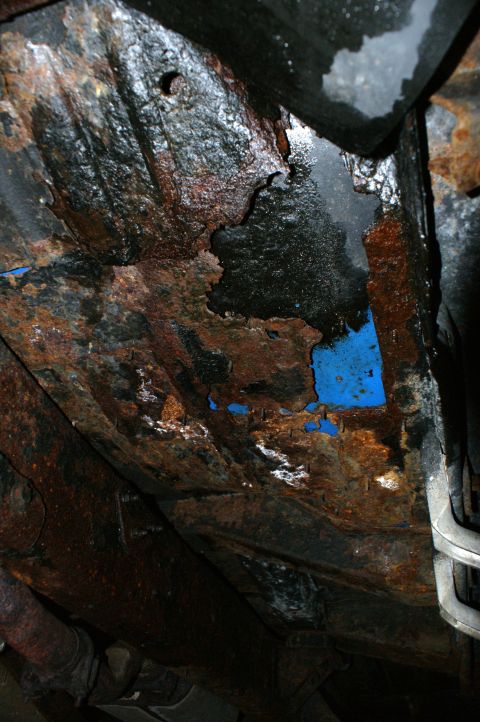 1979 Ford Bronco - The underside of a vehicle shows extensive rust and corrosion, indicating significant wear and potential structural compromise.