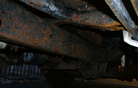1979 Ford Bronco - The undercarriage shows significant rust damage to the frame and suspension parts.