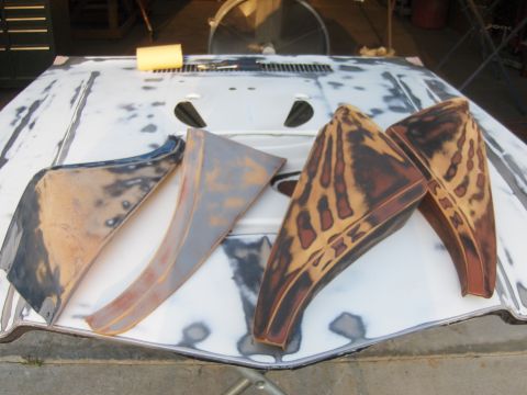 1980 Chevrolet Camaro - Four automotive parts are laid out on a car hood that appears to be prepped for bodywork.