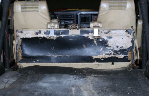 1979 Ford Bronco - Interior view of a 1979 Ford Bronco, highlighting worn and damaged upholstery on the rear seat.