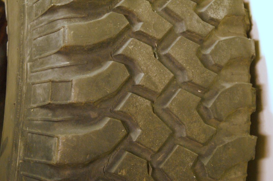 Close-up of a worn tire tread with large, blocky lugs and visible cracking